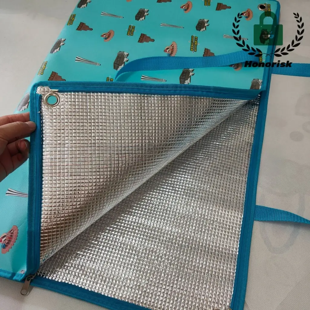 A stylish, folded waterproof picnic bag sitting on a wooden bench in a sunny park, ready for an outing.