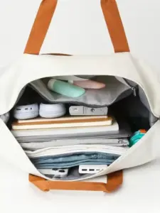 Front view of the white travel bag showing its sleek design and front pocket