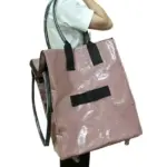 Pessoa que carrega uma grande bolsa de compras de PP de rodas com zíper - em excesso, rosa brilhante com alças pretas e rodas - mento de lado, Perfeito para destacar a versatilidade do design OEM ODM.