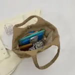 Bolsa acolchoada inchada para mulheres mostradas com notebooks e bolsa em uma superfície de tecido leve - perfeita para personalização OEM/ODM.