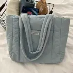 Oq rangdagi kiyimlar bilan simli idish oldidagi sim savatasi oldida yotgan ko'k rangdagi sumka pufagi oldida o'tiradi, OEM yoki ODMni sozlash uchun juda mos keladi.