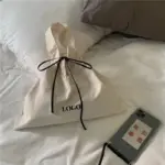 El llenç minimalista embruta el tote per a les dones, labeled "LOGO," Ideal per a la personalització ODM/OEM, s’asseu en un llit al costat d’un telèfon amb una funda de text xinès.